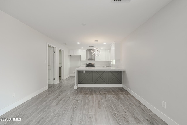 kitchen featuring decorative light fixtures, white cabinetry, kitchen peninsula, stainless steel range with electric stovetop, and wall chimney range hood