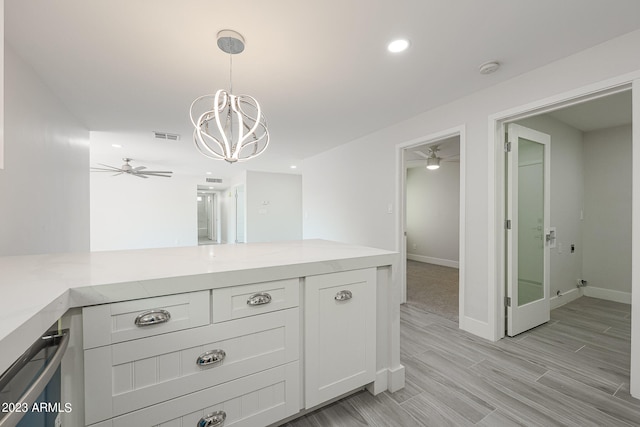 kitchen with kitchen peninsula, dishwashing machine, white cabinetry, decorative light fixtures, and ceiling fan with notable chandelier