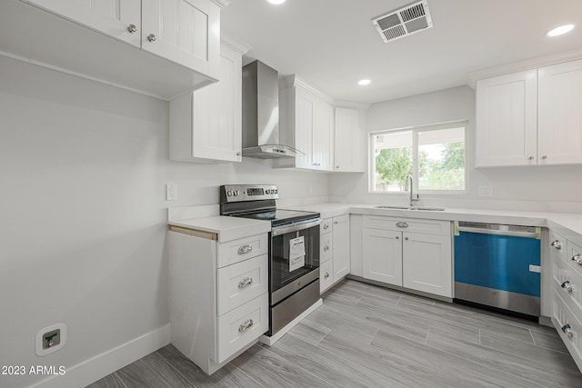 kitchen with appliances with stainless steel finishes, white cabinets, sink, and wall chimney exhaust hood