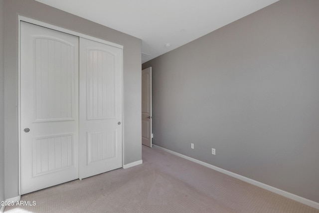 unfurnished bedroom featuring light carpet and a closet