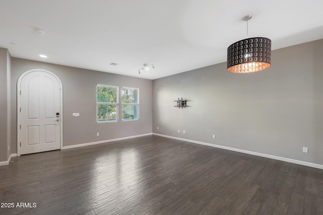 unfurnished room featuring dark wood-type flooring and a chandelier