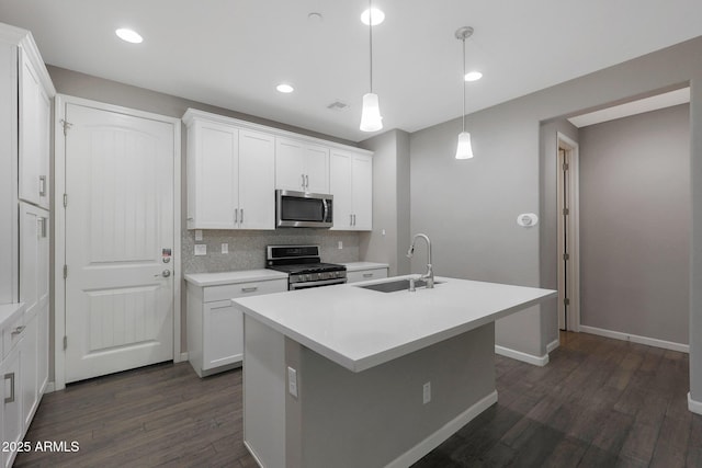 kitchen with sink, white cabinetry, hanging light fixtures, a center island with sink, and appliances with stainless steel finishes