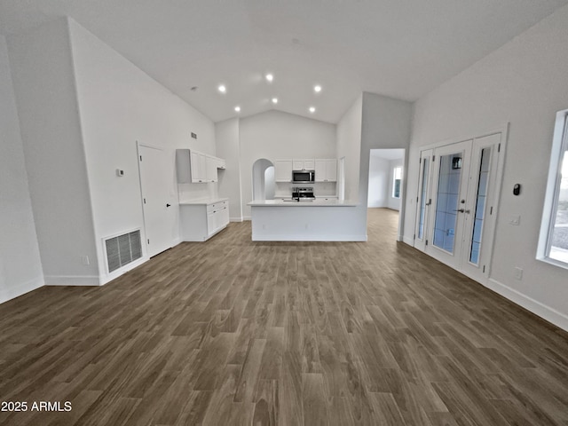 unfurnished living room featuring arched walkways, dark wood finished floors, recessed lighting, visible vents, and high vaulted ceiling