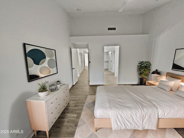 bedroom featuring a towering ceiling, visible vents, and wood finished floors