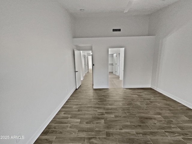 spare room with visible vents, baseboards, and dark wood-style flooring