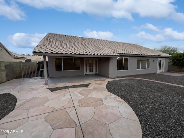 rear view of house with a tiled roof, fence, and stucco siding