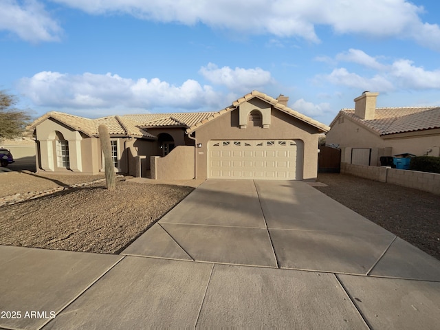 mediterranean / spanish-style home with a garage, concrete driveway, a tile roof, fence, and stucco siding