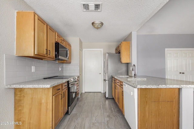 7506 W Sells Dr, Phoenix, AZ 85033 - kitchen with stainless steel appliances, a sink, backsplash, a peninsula, and light stone counters