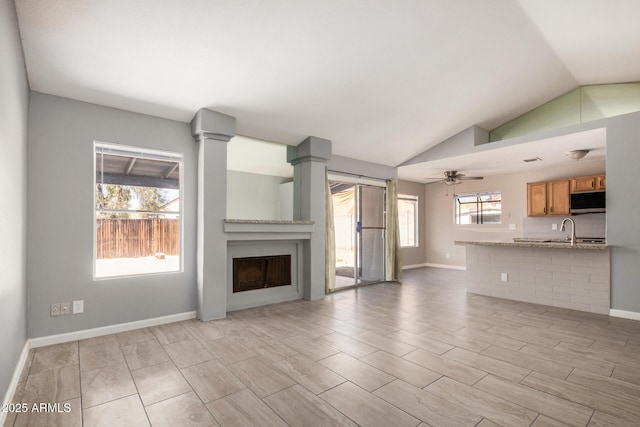 7506 W Sells Dr, Phoenix, AZ 85033 - unfurnished living room featuring a fireplace, a sink, lofted ceiling, ceiling fan, and baseboards