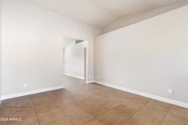 tiled empty room featuring lofted ceiling