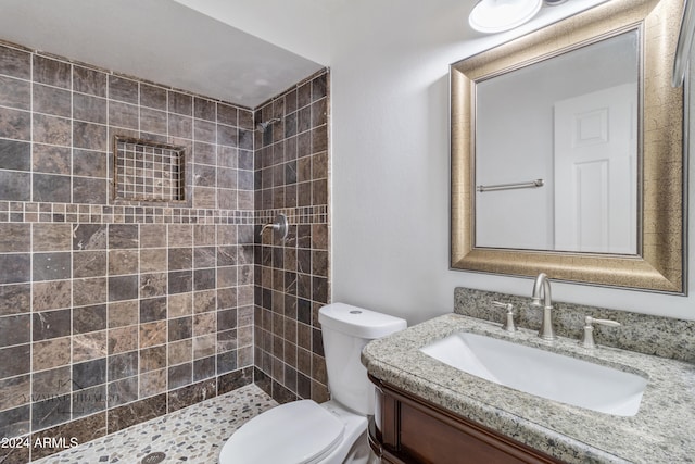 bathroom featuring a tile shower, vanity, and toilet