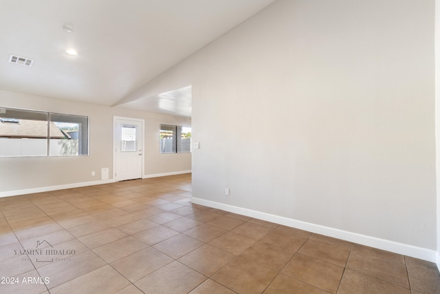 tiled empty room with a healthy amount of sunlight and lofted ceiling