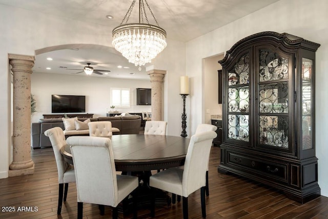 dining area with dark hardwood / wood-style flooring, ceiling fan with notable chandelier, and ornate columns