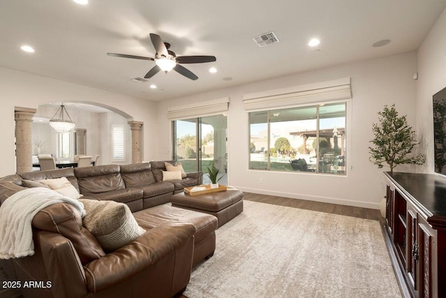 living room with decorative columns, wood-type flooring, and ceiling fan