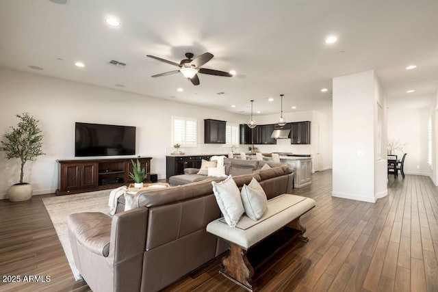living room featuring sink, dark wood-type flooring, and ceiling fan