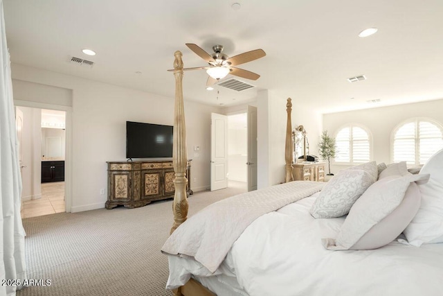 bedroom featuring ceiling fan, light colored carpet, and ensuite bath
