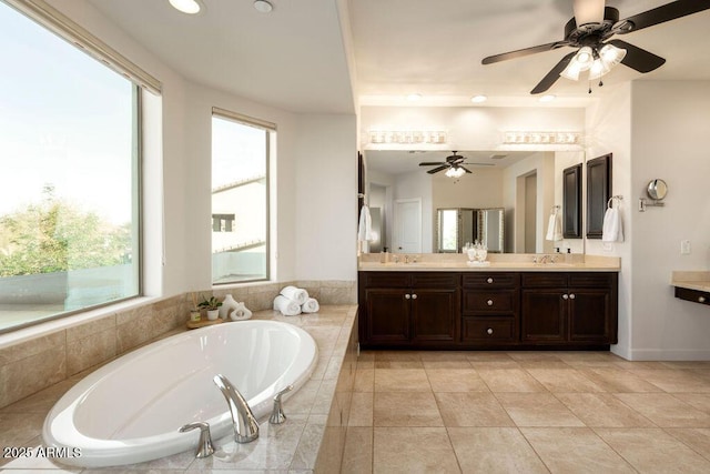 bathroom with a relaxing tiled tub, vanity, and tile patterned floors