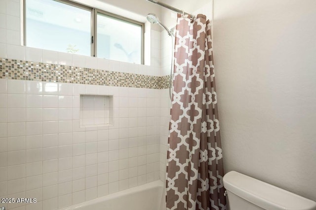 bathroom featuring shower / tub combo and toilet