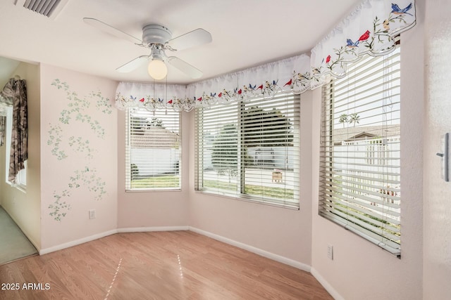empty room with light wood-type flooring, a ceiling fan, and baseboards