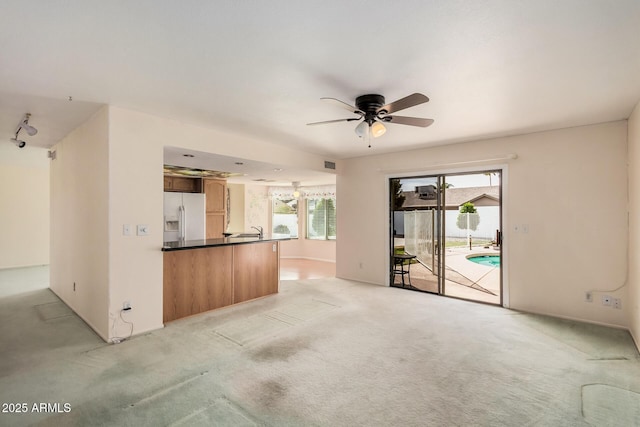 unfurnished living room featuring a ceiling fan and light carpet