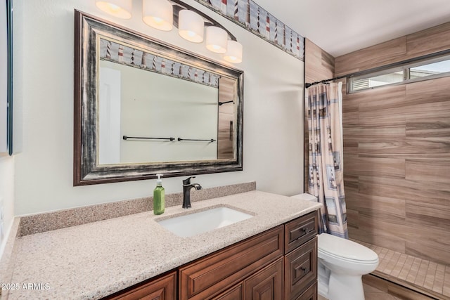 bathroom with tiled shower, toilet, and vanity