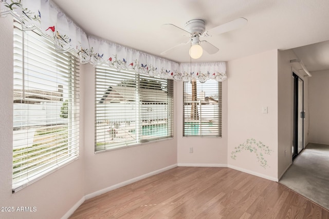 unfurnished dining area with light wood finished floors, a ceiling fan, and baseboards