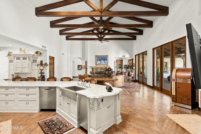 kitchen with white cabinetry, light parquet floors, beam ceiling, sink, and stainless steel dishwasher