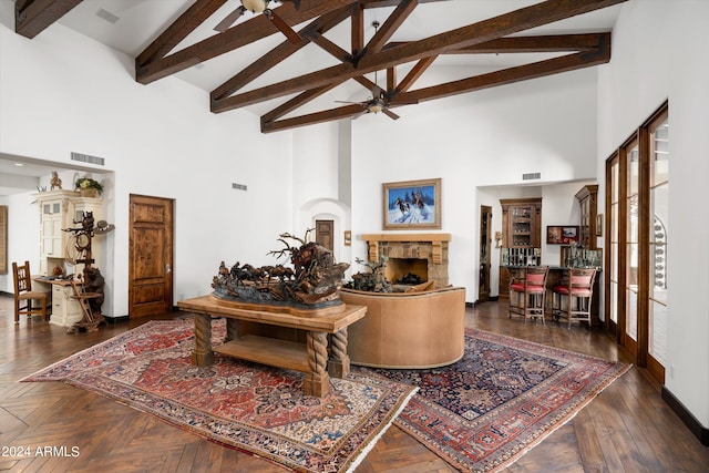 living room with high vaulted ceiling, beam ceiling, dark parquet floors, a stone fireplace, and ceiling fan