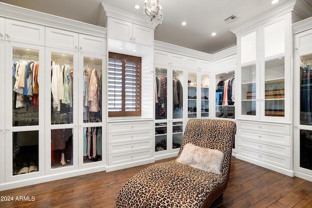 walk in closet with a notable chandelier and dark wood-type flooring