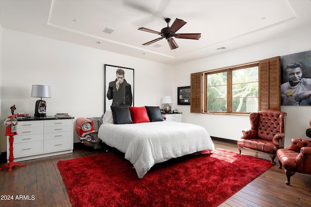 bedroom featuring ceiling fan, dark hardwood / wood-style floors, and a tray ceiling