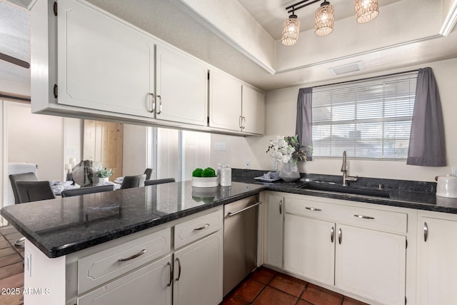 kitchen with a sink, a peninsula, white cabinets, dishwasher, and dark tile patterned flooring