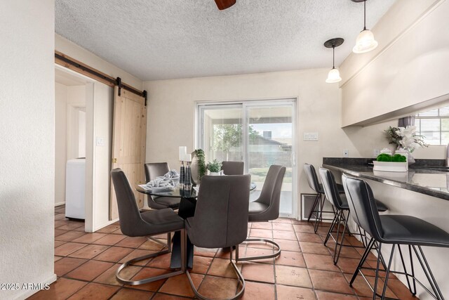 dining room featuring a barn door, tile patterned floors, a textured ceiling, and washer / dryer