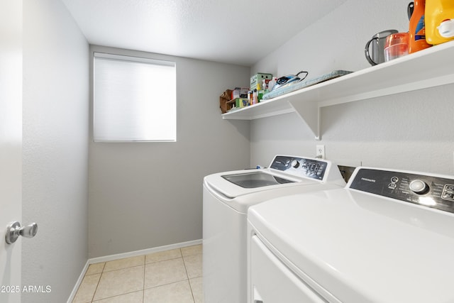 washroom featuring light tile patterned flooring, laundry area, washer and dryer, and baseboards