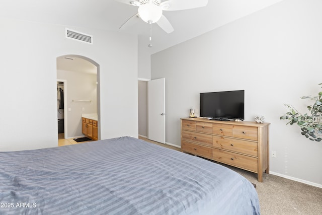 bedroom with visible vents, light carpet, arched walkways, baseboards, and vaulted ceiling