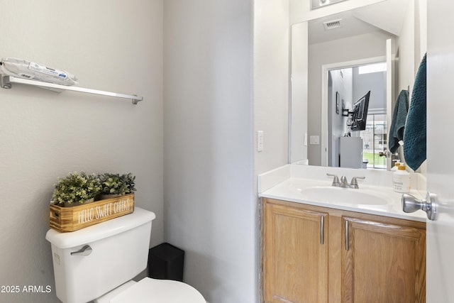 bathroom featuring visible vents, toilet, and vanity