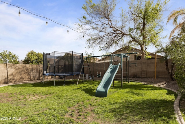 view of play area with a trampoline, a fenced backyard, and a yard