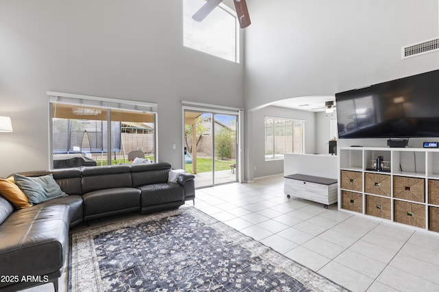 tiled living area featuring visible vents, a high ceiling, and ceiling fan