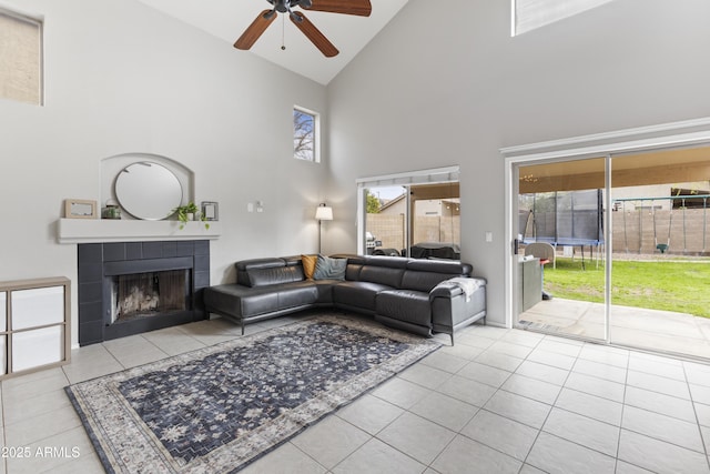 living area with tile patterned floors, a ceiling fan, lofted ceiling, and a tile fireplace