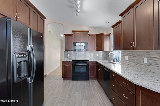 kitchen featuring sink, light wood-type flooring, tasteful backsplash, light stone countertops, and black appliances