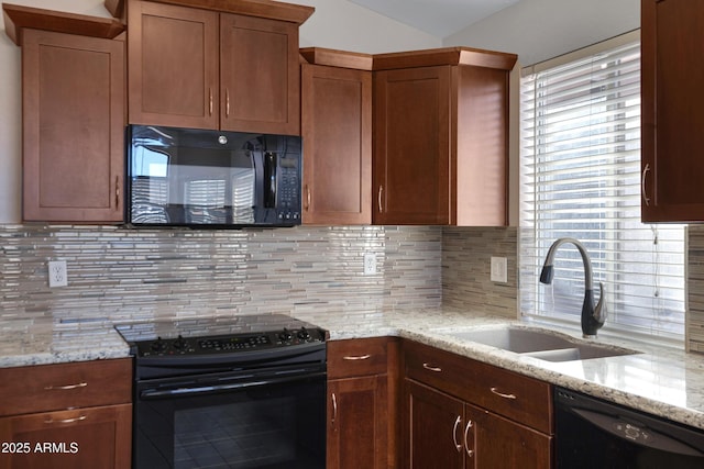 kitchen featuring black appliances, light stone countertops, tasteful backsplash, and sink