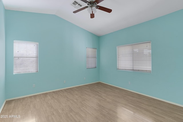 spare room with light hardwood / wood-style floors, vaulted ceiling, and ceiling fan