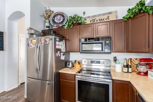 kitchen with dark wood-type flooring, stainless steel appliances, and lofted ceiling