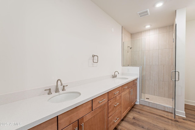 bathroom featuring a shower stall, visible vents, a sink, and wood finished floors