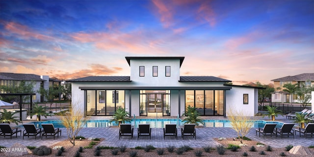 back of property with stucco siding, a standing seam roof, a patio area, fence, and metal roof