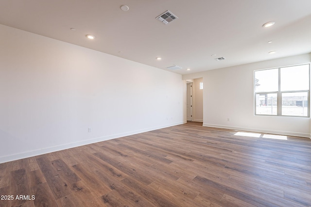 empty room with recessed lighting, visible vents, baseboards, and wood finished floors