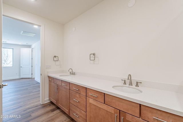 bathroom featuring double vanity, visible vents, a sink, and wood finished floors