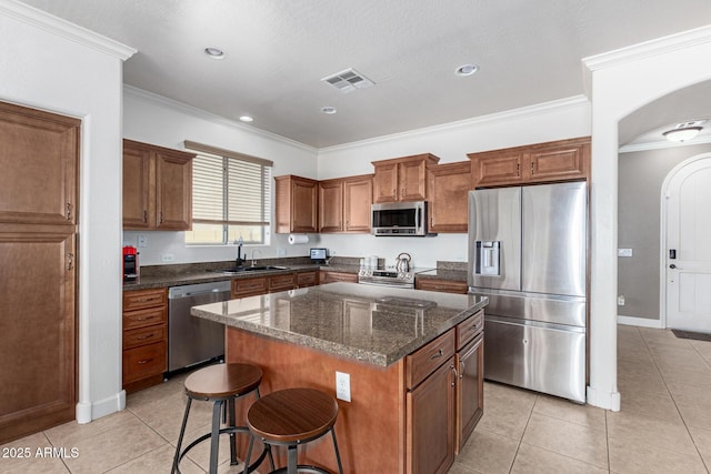 157 N 110th Ave, Avondale, AZ 85323 - kitchen featuring appliances with stainless steel finishes, a sink, arched walkways, a kitchen bar, and crown molding