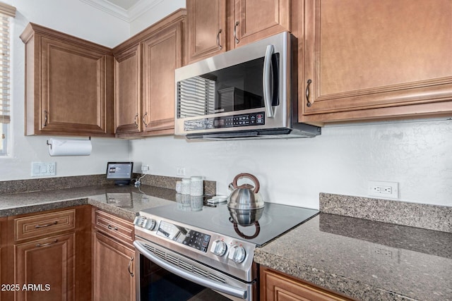 157 N 110th Ave, Avondale, AZ 85323 - kitchen featuring stainless steel appliances, ornamental molding, brown cabinetry, and dark stone countertops