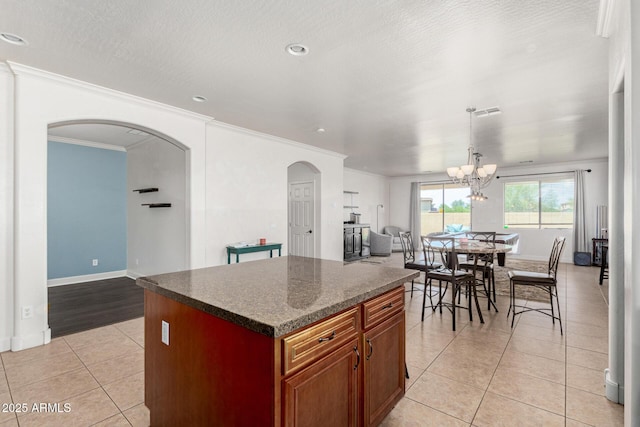 157 N 110th Ave, Avondale, AZ 85323 - kitchen featuring arched walkways, light tile patterned floors, crown molding, a kitchen island, and a chandelier