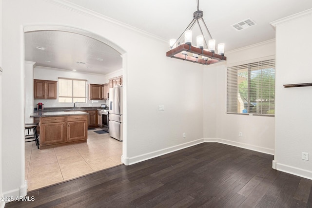 157 N 110th Ave, Avondale, AZ 85323 - unfurnished dining area featuring arched walkways, hardwood / wood-style floors, a chandelier, crown molding, and baseboards
